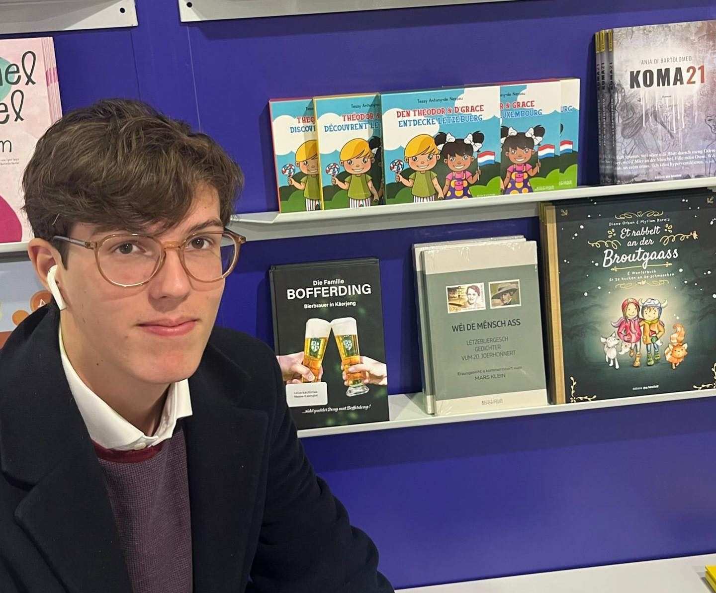 Габриел със слушалки пред библотека с книги