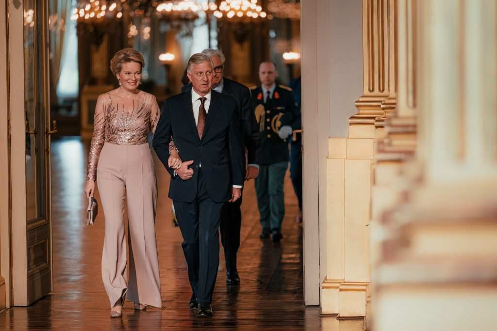 Крал Филип в тъмносин костюм и кралица Матилда в бледорозов гащеризон Elie Saab вървят под ръка.