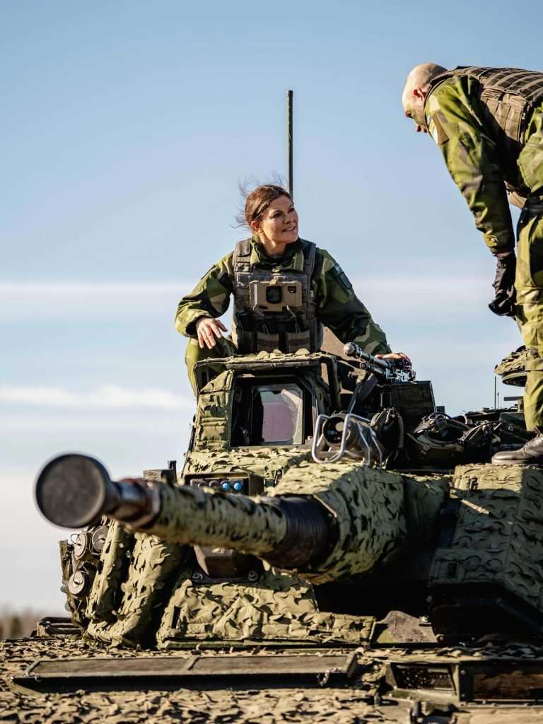 Престолонаследничката Виктория, седяща на купола на голям боен танк