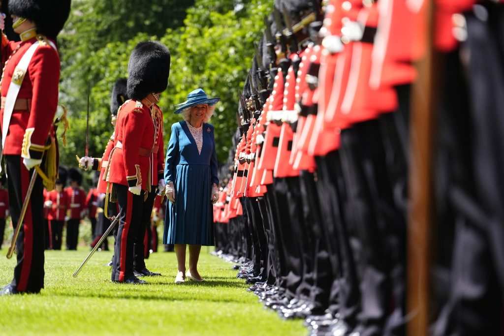Кралицата се усмихва пред строените на тревата войници. 