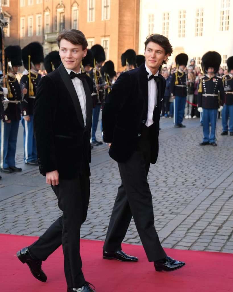 Феликс и Николай на червен килим в тъмни смокинги.