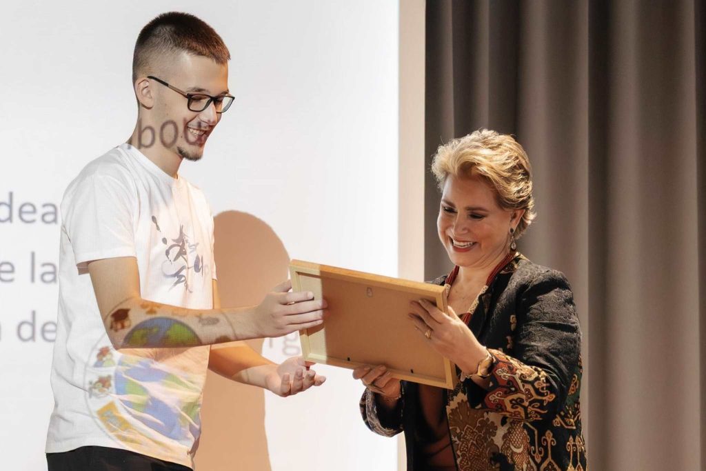 Младеж от Stand Speak Rise Up! връчва подарък на усмихнатата велика херцогиня Мария-Тереза